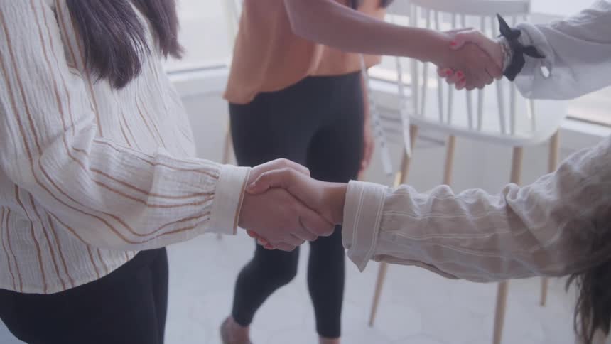 Four people shake hands and greet each other