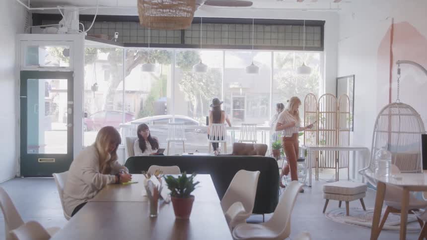 A bright modern cafe where women are working chatting and relaxing in a cozy setting