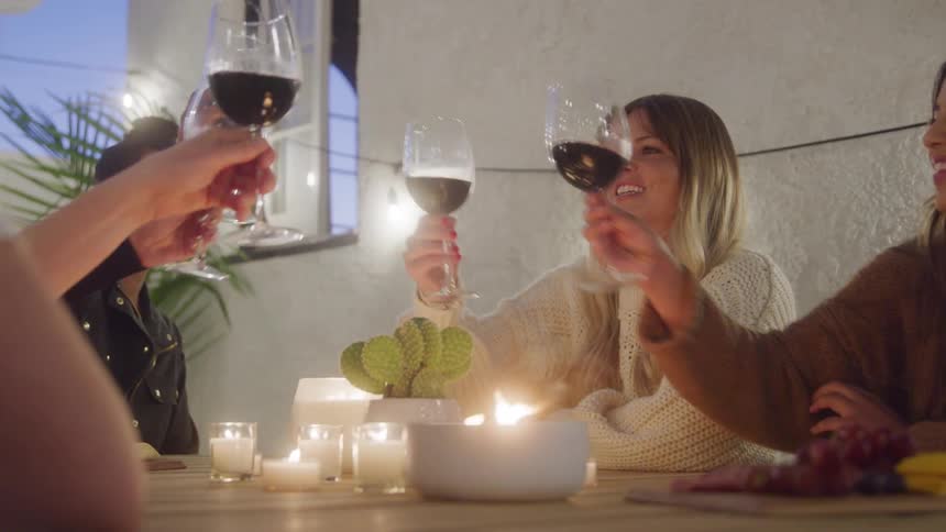 4 women toasting and drinking wine at a table