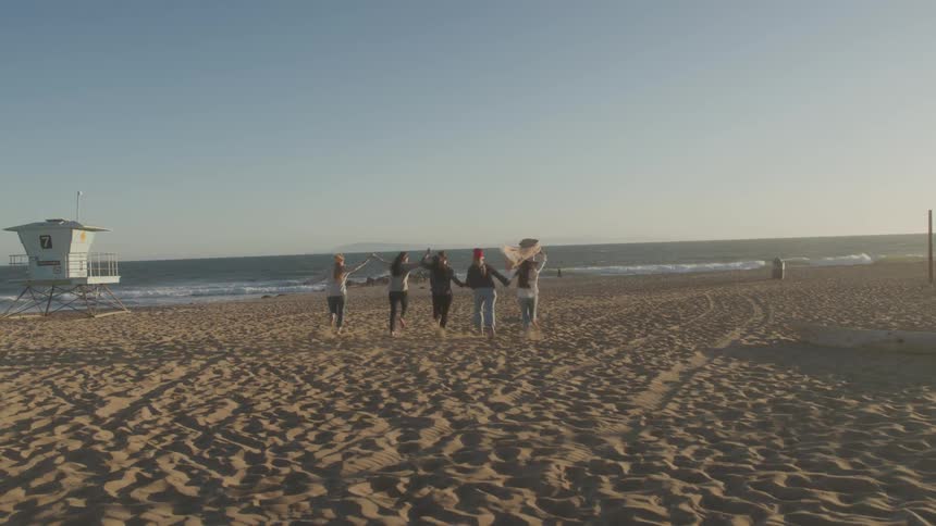 A group of women run down the beach