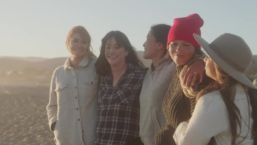 The women are standing together on the beach