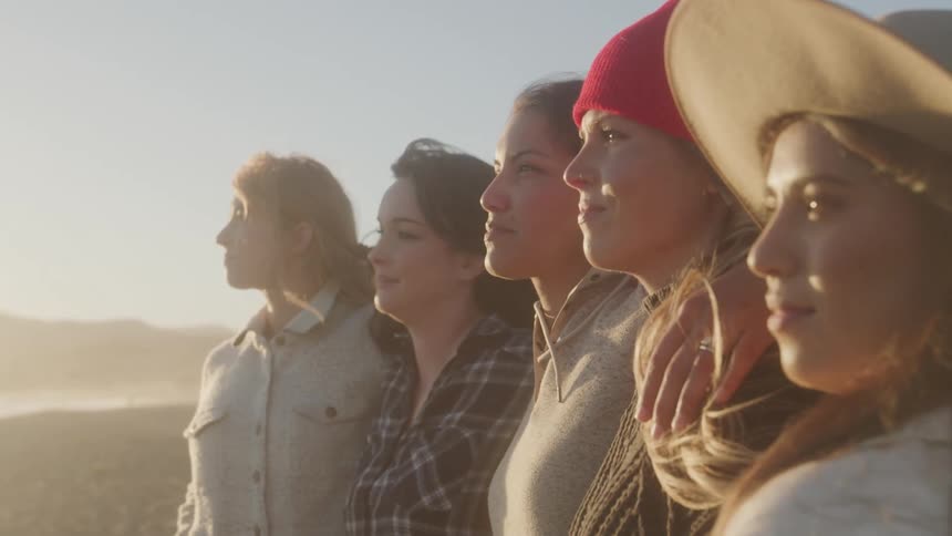The wind blows the hair of the women on the beach