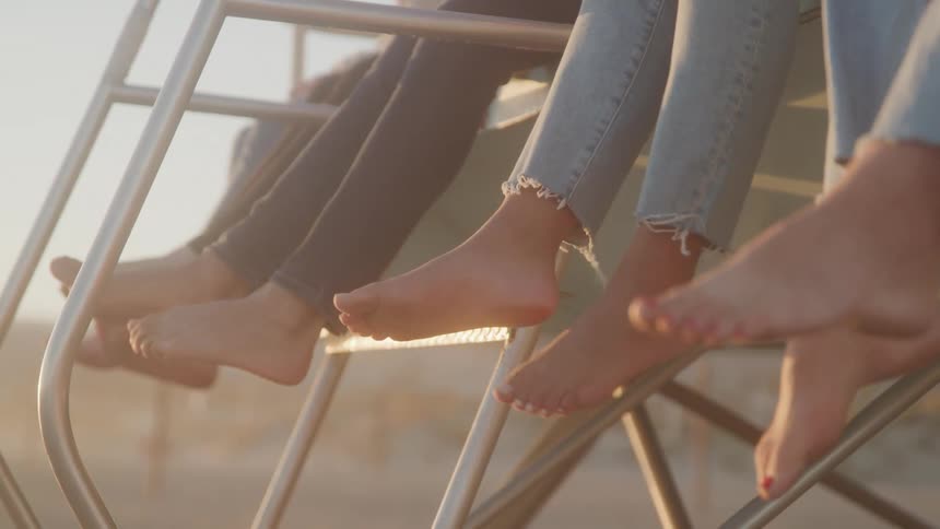 Feet of barefoot people and people wearing jeans swinging outdoors