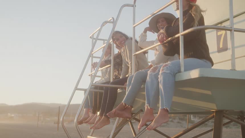 Women are sitting up on the lifeguard stand and talking