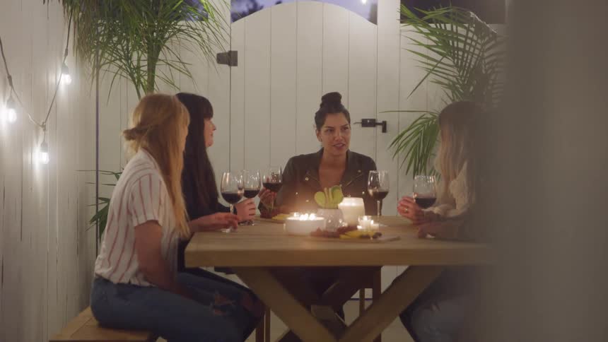 Friends enjoy a cozy outdoor dinner together by candlelight