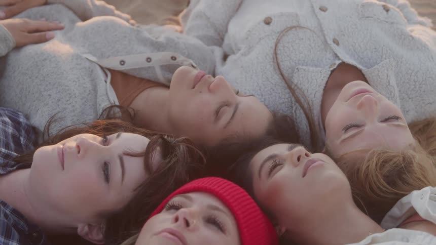 Heads of five females laying on the floor with closed eyes at sunset