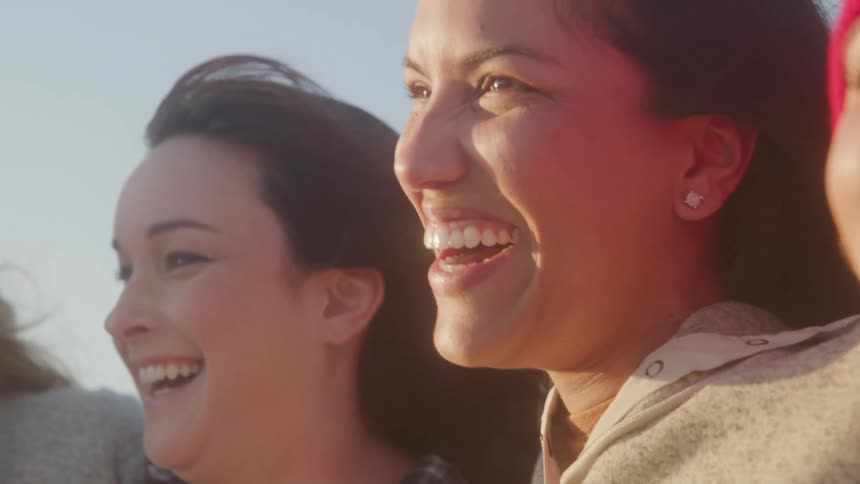 A close up of a group of happy friends laughing on a sunny day