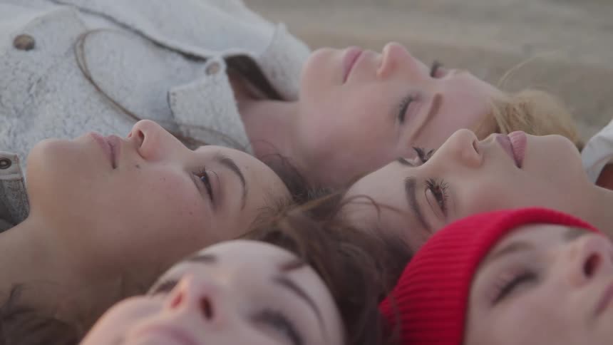 Women are laying on the sand together