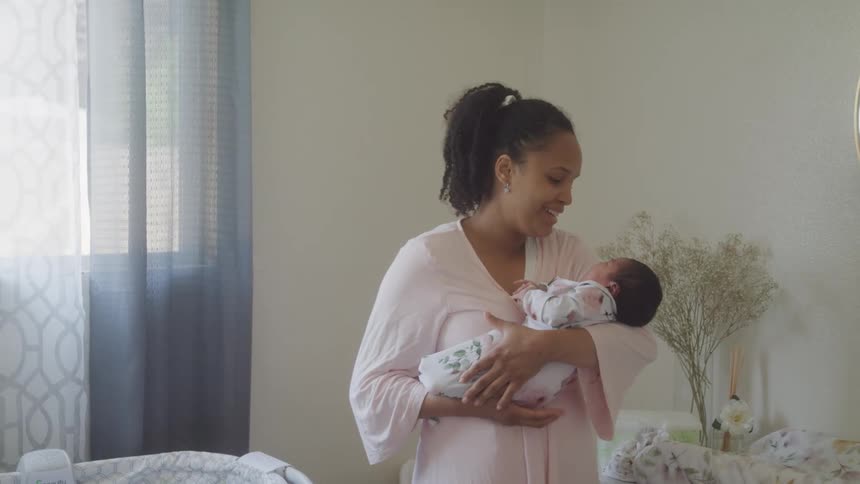 A woman holding a baby in her arms talking to the baby in a room
