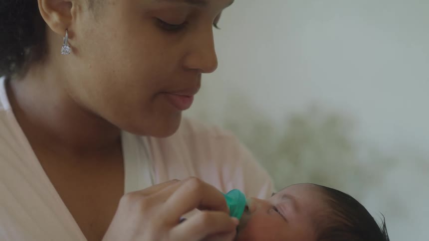 A woman gently gives a pacifier to her baby while holding them close