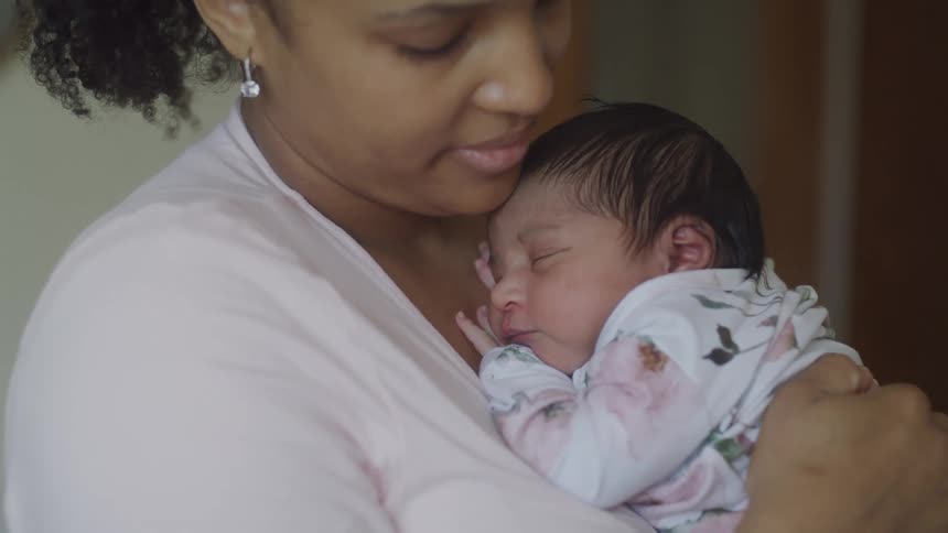 A mother lovingly cradles her sleeping newborn in a quiet moment