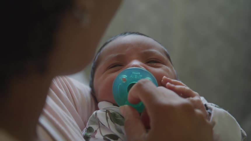 A mother gives her crying son a pacifier