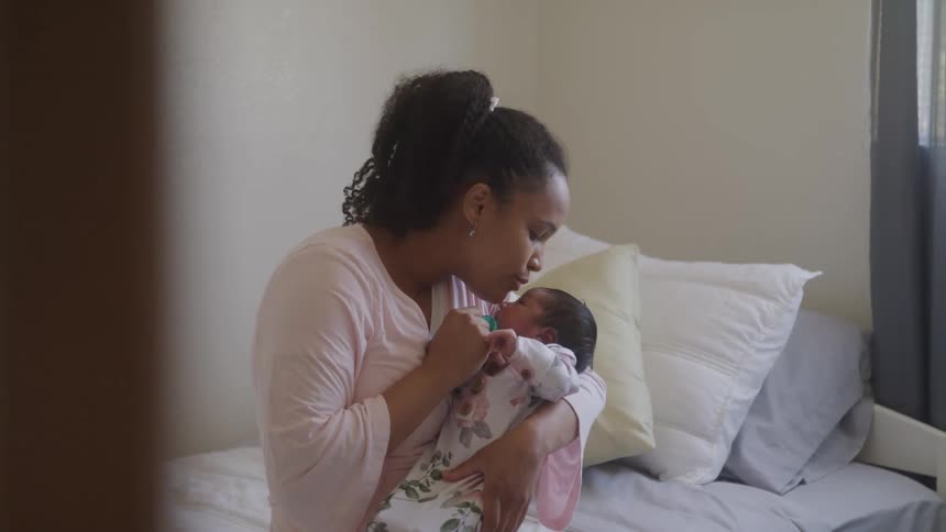 Mother sitting on a bed holding her newborn baby