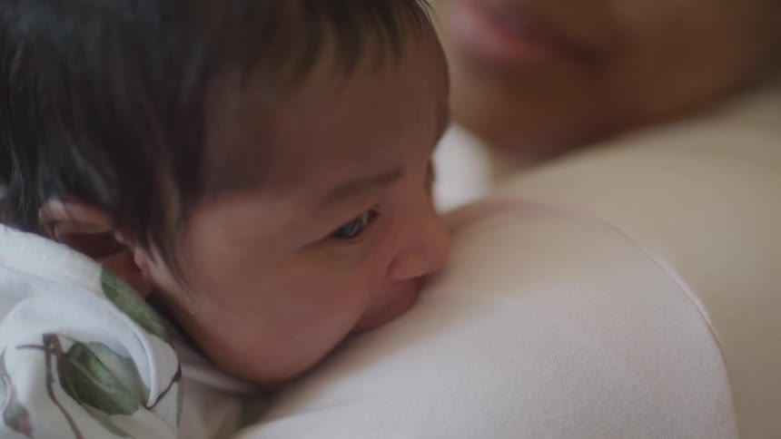 The newborn is biting his mothers arm