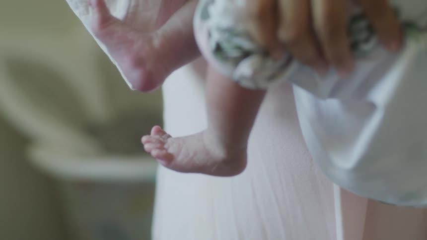 A close view shows the small feet of a baby being held by a person