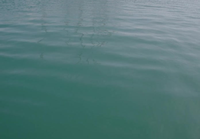 Turquoise water reflects the faint grid pattern of an overhead structure in soft diffused light