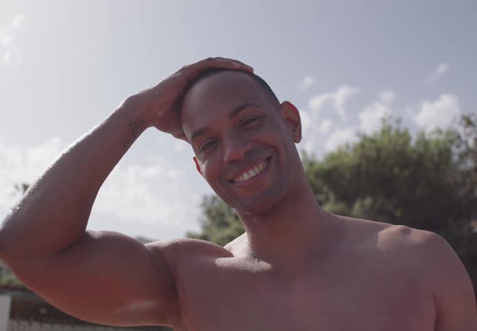 A man rubs his head and smiles