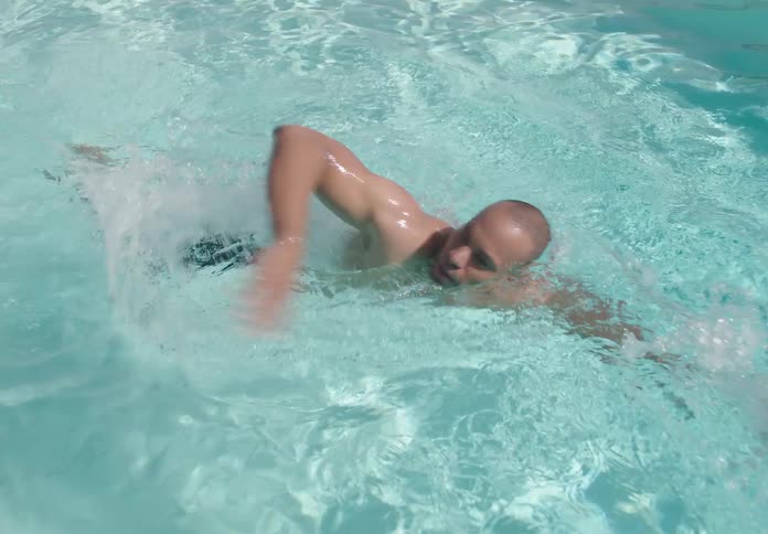 The man swims by in the pool