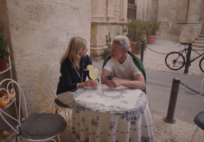 A couple enjoys drinks together at an outdoor cafe in a charming old street
