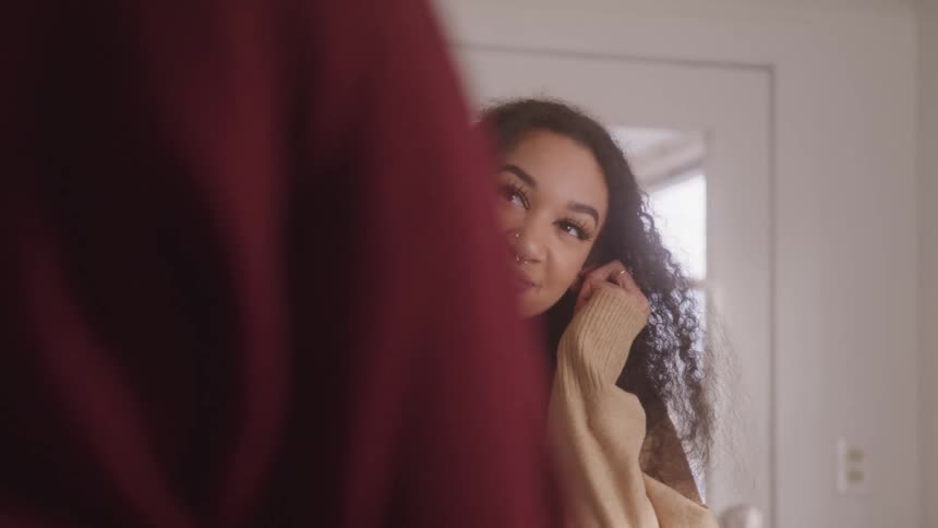 Curly haired teenage girl with happy expression talking to another person