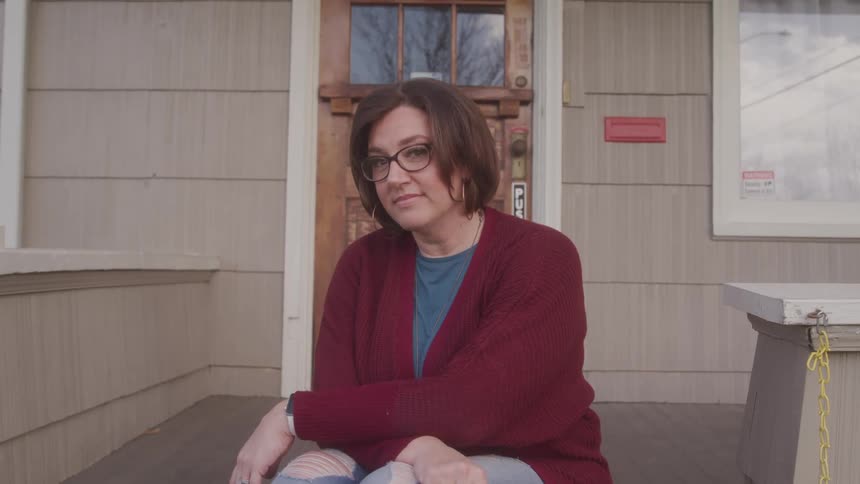 A woman sits on her front porch steps