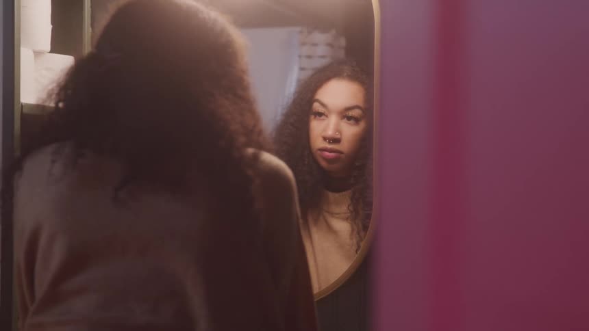A woman leans in front of the mirror