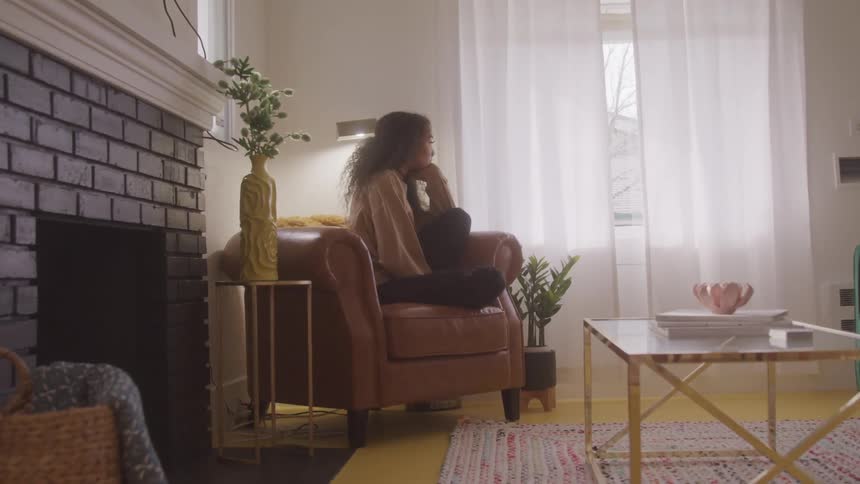 A woman is sitting and looking out her window