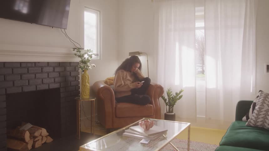 The woman is sitting on the chair using her phone