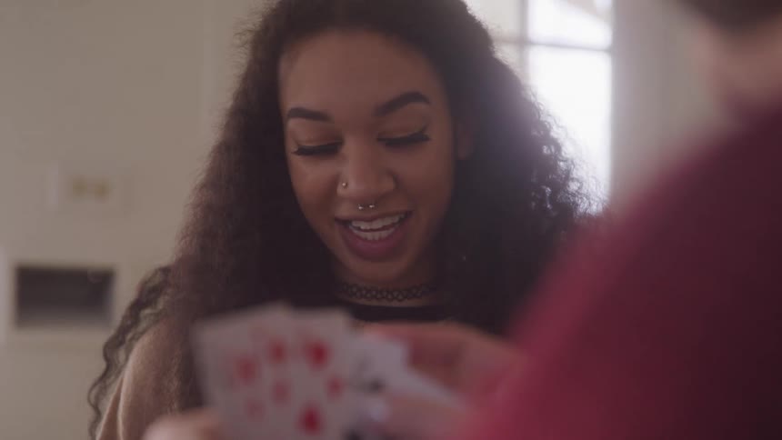 A woman smiles and talks while playing cards