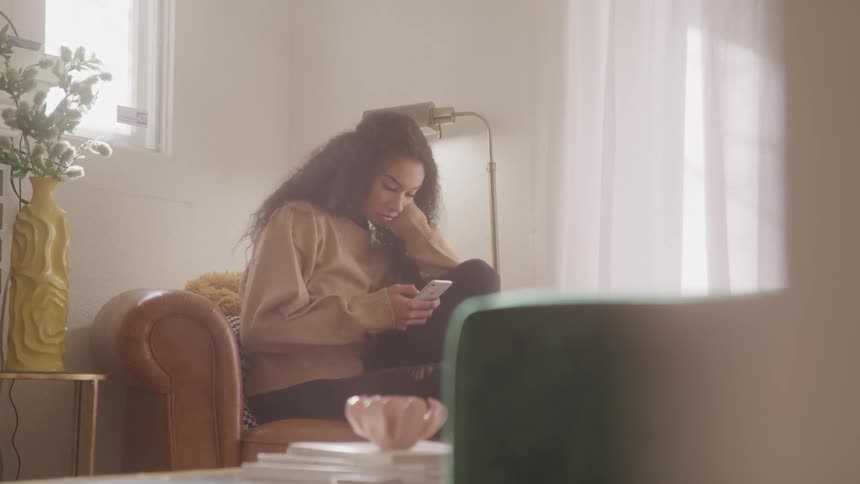 A woman sitting on the couch using her cellphone