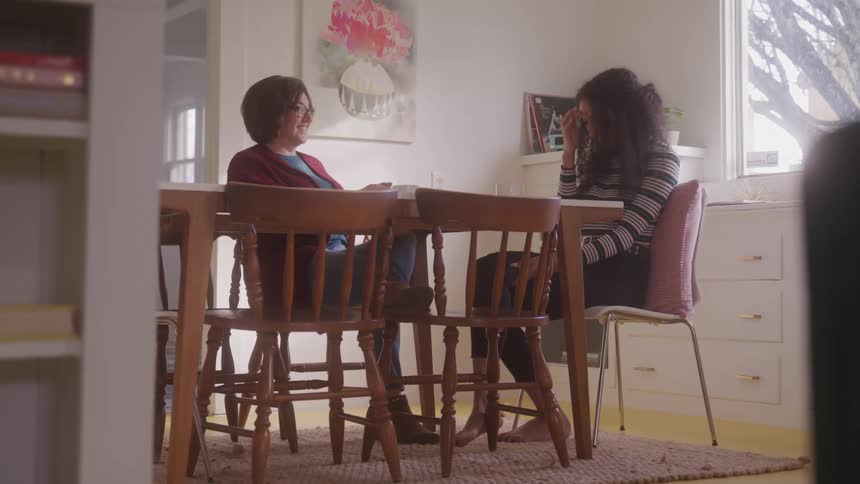 Two women sitting at a table talking during the day