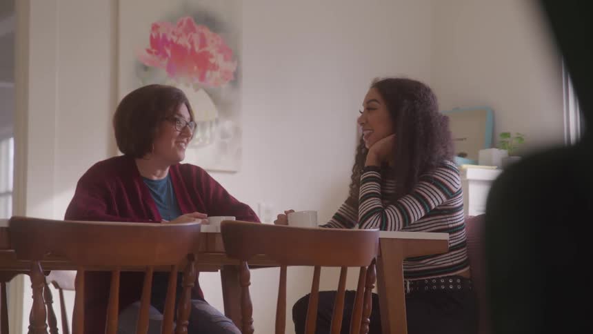 Mother and daughter chat warmly over coffee at a table