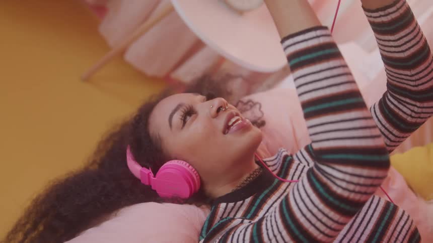 Woman interacting with smartphone while lying down and using headphones