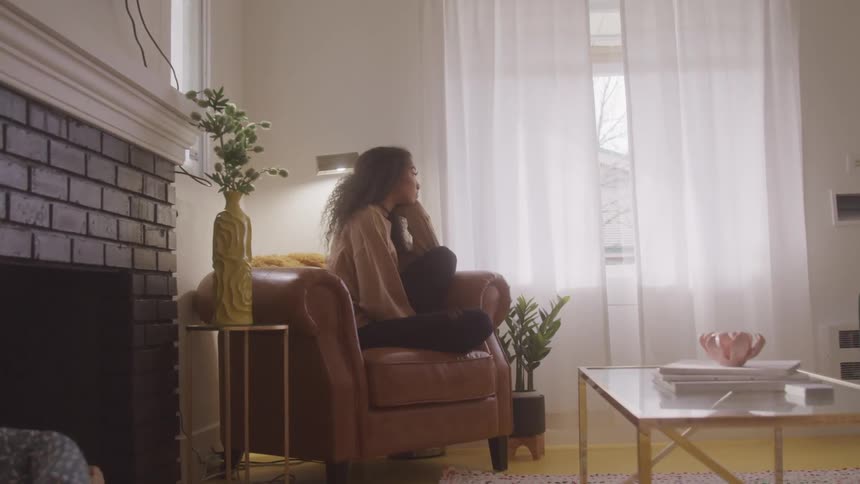 Thoughtful woman sitting in an armchair in the living room