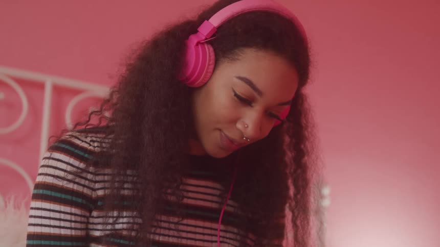 Curly haired woman with pink headphones