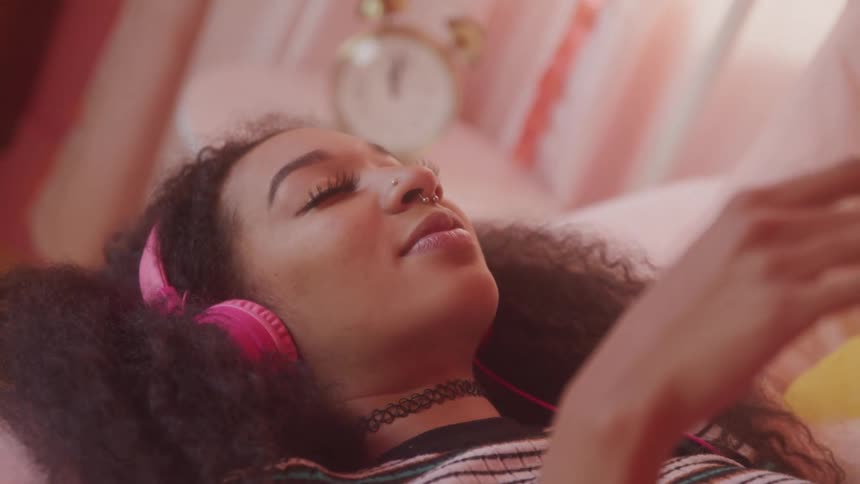 A woman smiles while listening to music on her headphones