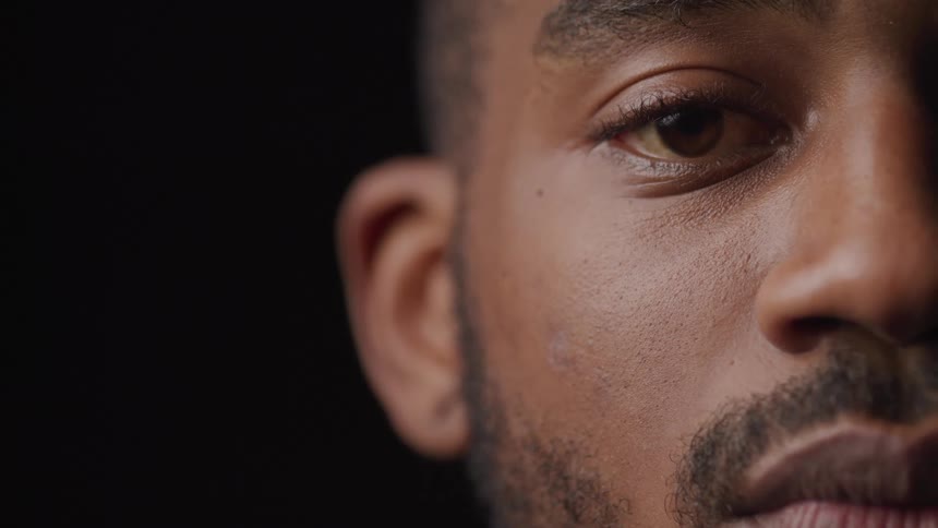 A closeup shot focuses on a persons face framed against a dark background