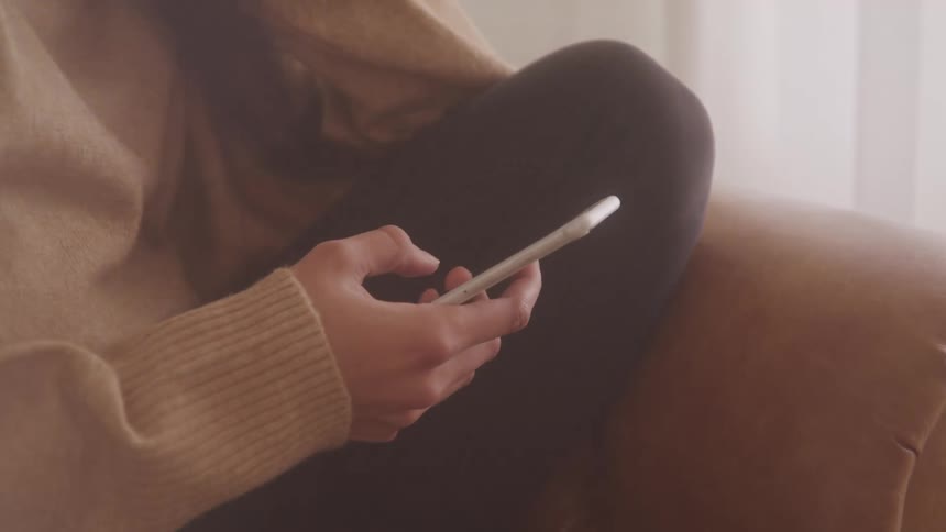 Female sitting on a leather couch texting on cell phone