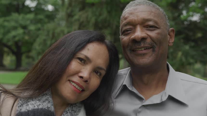 A happy couple poses together outdoors in a park