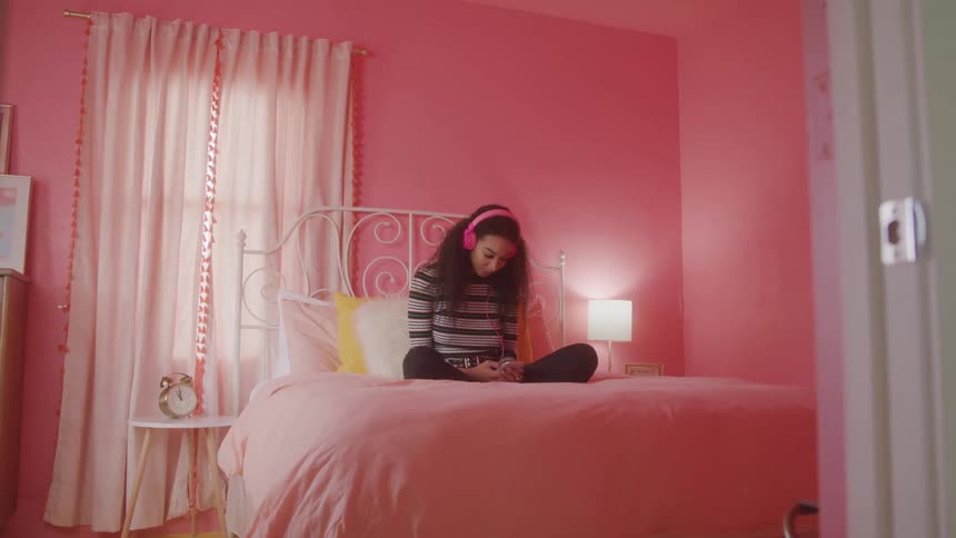 A girl sits in bed listening to music