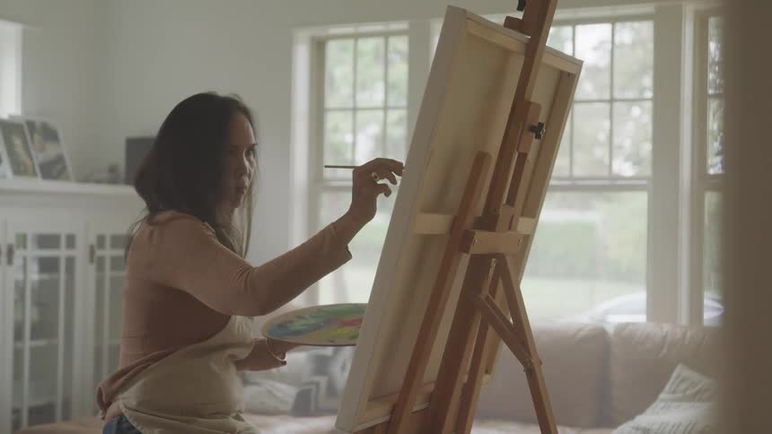 Woman in a living room painting on a white canvas