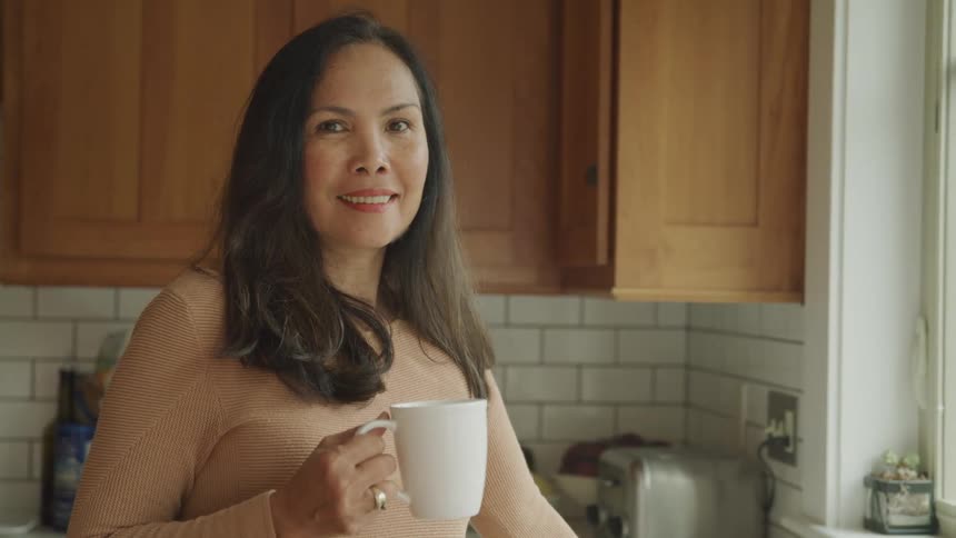 Smiling woman holding a mug in the kitchen
