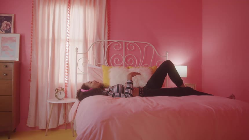 A girl lies in bed listening to music