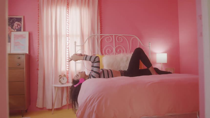A girl lays in bed on her phone