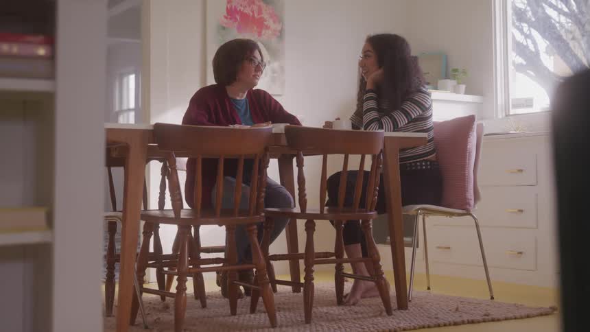 Two women sitting at a table during the day talking