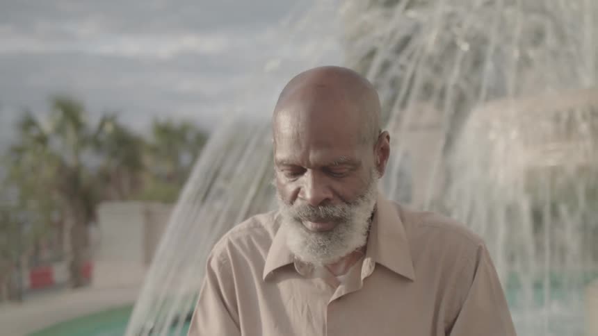A man sits in front of a fountain