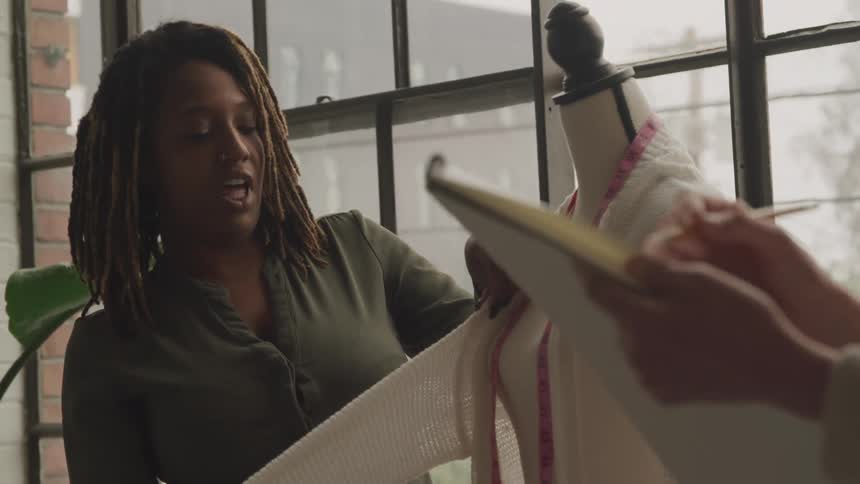 Two fashion designers showing a garment on a mannequin