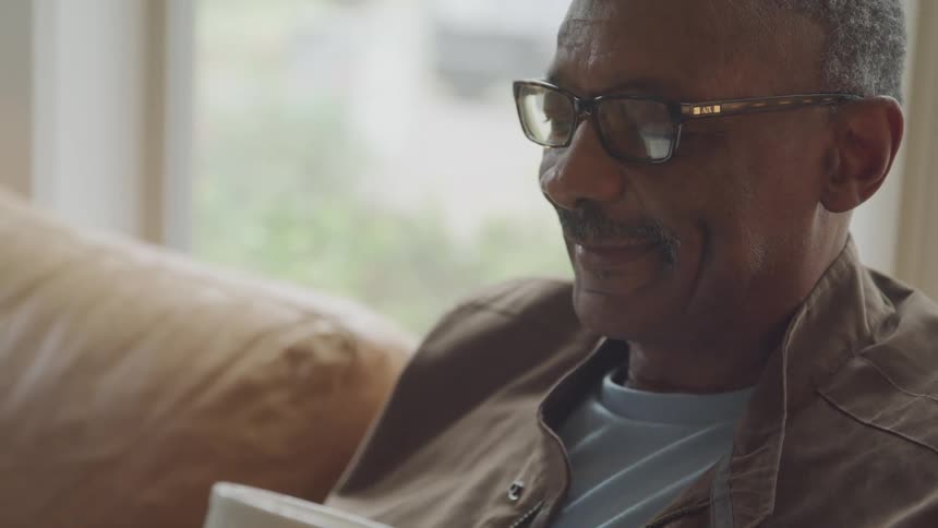 A man relaxes indoors while sipping from a white mug