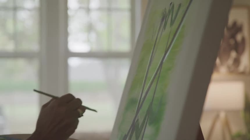 Hand with a brush painting a canvas