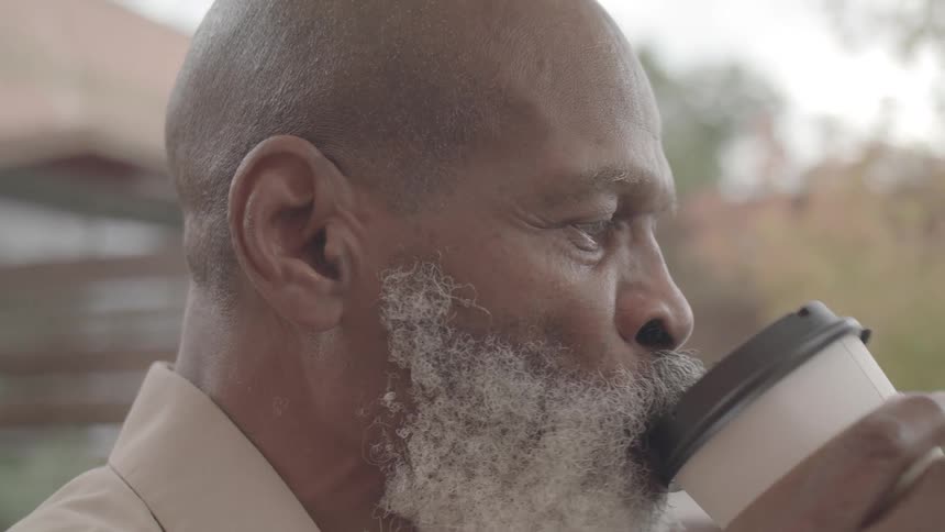 White bearded man drinking coffee from a disposable cup